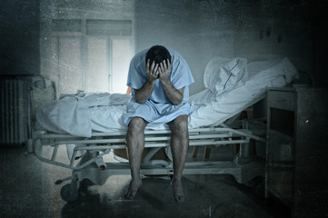 desperate man sitting at hospital bed alone sad and devastated suffering depression crying at clinic