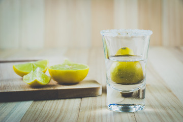 Vodka shot and salt sea, lemon  on wooden table