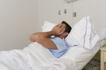 Fototapeta na wymiar young patient man lying at hospital bed resting tired looking sad and depressed worried