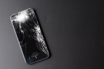 Smartphone with broken screen on dark background