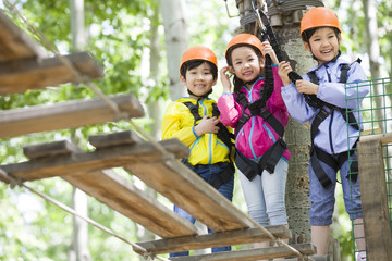 Happy children playing in tree top adventure park