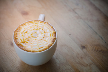 A Cup of hot latte art coffee on wooden table