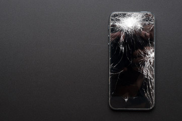 Smartphone with broken screen on dark background