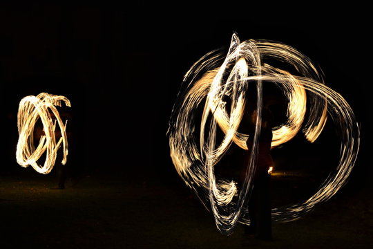 Fire show - artists juggling with burning tools in the dark