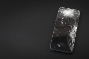 Smartphone with broken screen on dark background