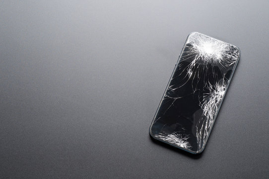 Smartphone with broken screen on dark background
