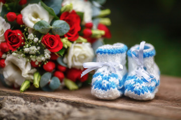 Wedding bouquet of roses and baby booties on wooden background