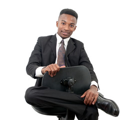 young man seated on chain smiling wearing black suit and tie