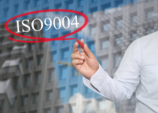 Hand of young businessman write the word ISO 9004 on skyscrapers