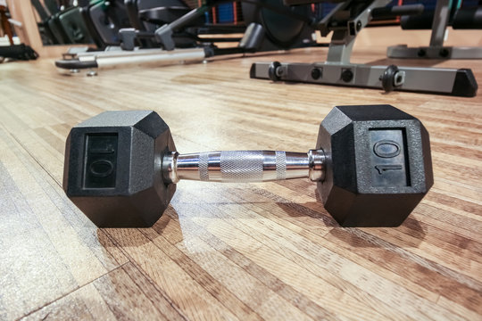 Closeup dumbell on the floor in fitness club with mirror reflection, fitness concept
