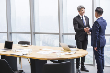 Businessmen shaking hands in meeting room