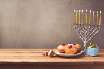 Hanukkah holiday sufganiyot and menorah on wooden table over vintage background © maglara