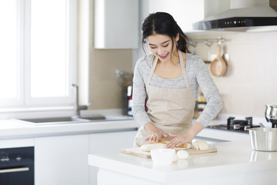 Young woman kneading dough on cutting board