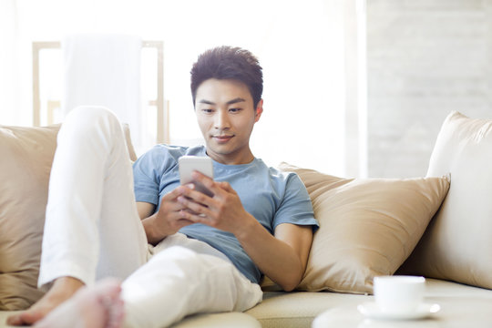 Young man using smart phone on the sofa