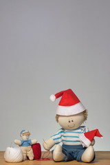 A doll wearing a christmas hat sewing another hat for a small doll