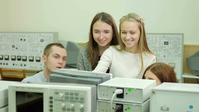 Young student engineers team work in the University of the electrical laboratory. They counsel and test oscilloscope voltmeter readings on the instruments. Future scientists