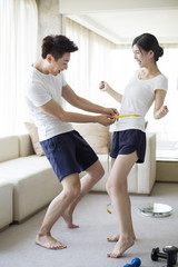 Obraz premium Young man measuring the waist of his wife