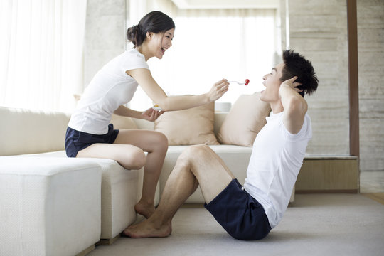 Young couple eating while exercising at home