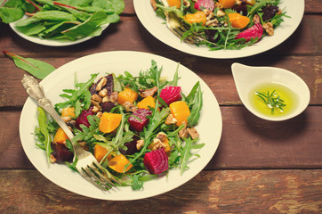 Fall salad with greens, arugula, walnuts, beetroot and roasted squash, pumpkin on wooden background