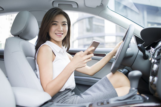 Confident businesswoman holding smart phone in a car