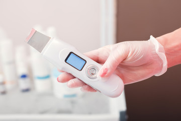 Gloved hand holding the ultrasonic scraber.