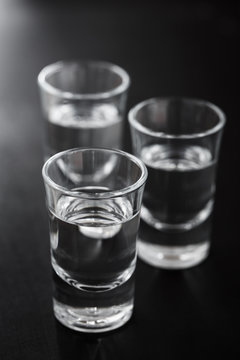 Three glasses of vodka on a black background