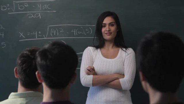 MS Young woman writing mathematical formula on blackboard in classroom