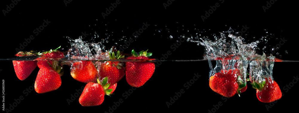 Wall mural Strawberries splashing into water