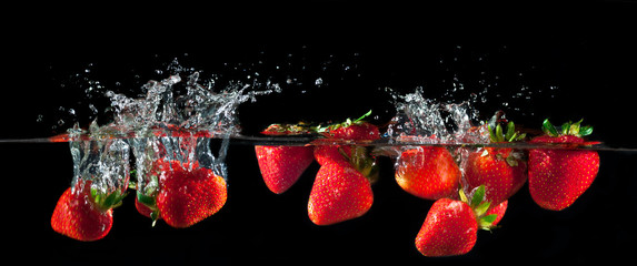 Fototapeta na wymiar Strawberries splashing into water