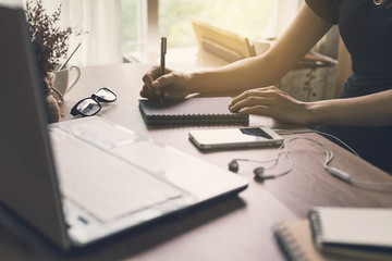 woman writing on notebook at workplace