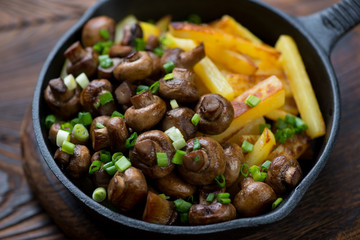 Closeup of a cast-iron skillet with fried champignons and potato