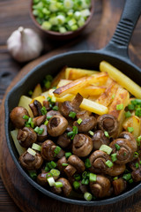 Roasted champignons served with potato and green onion, close-up