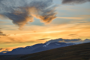 Fototapeta na wymiar Bright yellow sunset over the highest swedish mountains in Sarek