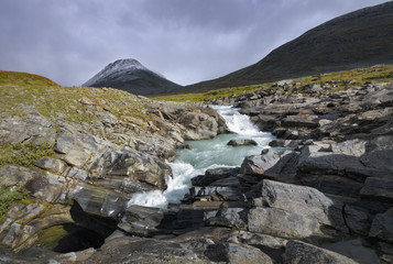 Turbulent river swirling fed glacial melt water with dramatic mo