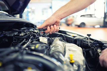Fototapeta na wymiar KFZ Mechaniker repariert Motor eines Fahrzeugs in der Autowerkstatt - Close Up Hand mit Werkzeug im Motorraum
