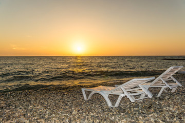 Fototapeta na wymiar Sunset on the beach. Two sun loungers.