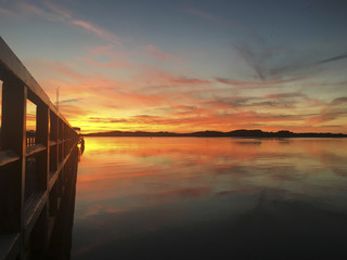 Fototapeta na wymiar feuriger Sonnenuntergang am See mit Steg Müritz