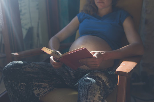 Pregnant woman reading by window