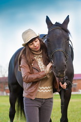 Obraz premium Woman and horse, beige pullover, leather jacket, jeans, hat, cl