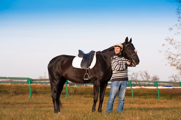 Man nearby horse, striped pullover, blue jeans, hat, landscape