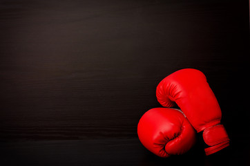 Red boxing gloves on a black background in the corner of the frame, place for text