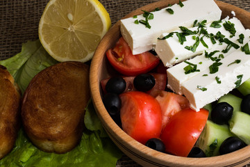 Greek salad with feta cheese and vegetables on wooden plate
