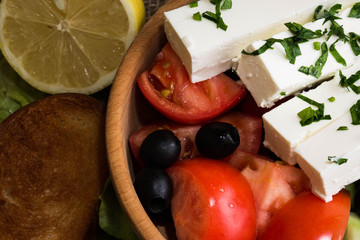Greek salad with feta cheese and vegetables on wooden plate
