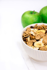 White bowl with rye flakes muesli on white towel with green apples, copyspace for text, white background
