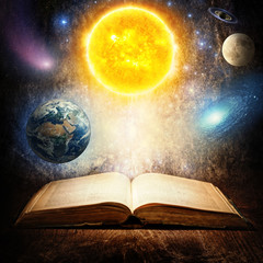 Opened magic book with sun, earth, moon, saturn, stars and galaxy. Concept on the topic of astronomy or fantasy. Elements of this image furnished by NASA.