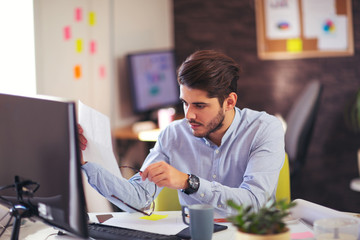 Handsome young smiling businessman working with documents in off