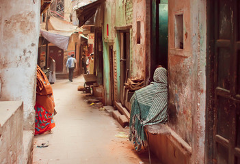 Obraz na płótnie Canvas Poor people in long traditional scarfs sitting on street