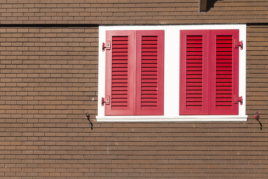 Closeup of a swiss chalet with brown wall, white frame and red window shutters