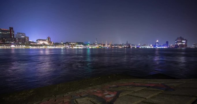Hamburg, Germany - panorama view over river Elbe from south shore to illuminated skyline with Landungsbruecken, church Michel and Elbphilharmonie at night - Timelapse without motion - April 2016