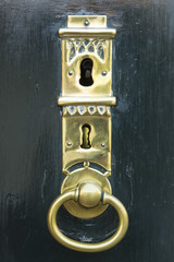 A dark green painted wooden door with a beautifully forged golden key hole